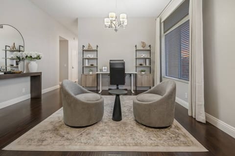 The workspace features swivel chairs for easy movement & flexibility. Its open layout seamlessly connects to the living room, creating a spacious, airy environment. This setup allows for multitasking and socializing, perfect for work & relaxation.