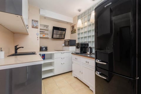 A modern kitchenette with sleek white cabinets and all the essentials, perfect for preparing meals in a compact yet functional space.
