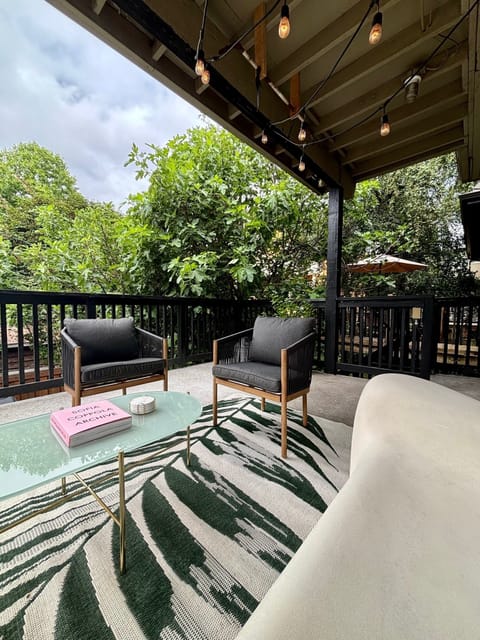 Back covered deck with lounge chairs and string lights. 