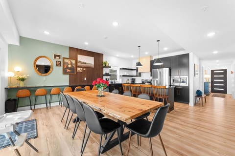 Custom live-edge dining table seating 10, plus additional counter seating in the modern kitchen.