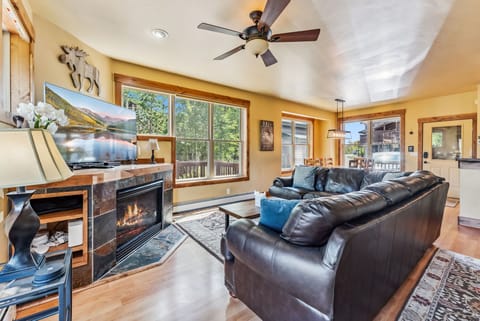 Living Room: Large leather sectional couch, gas fireplace, 65” TV, access to upper deck