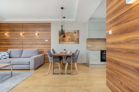 Modern living room with gray couch, wooden accent wall, and warm lighting.