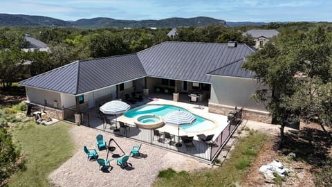 A bird`s-eye view of the property showcasing a relaxing pool, hot tub, and fire pit area, perfect for outdoor fun with family or friends.