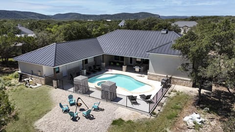 A bird's-eye view of the property showcasing a relaxing pool, hot tub, and fire pit area, perfect for outdoor fun with family or friends.