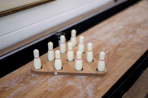 Mini tabletop bowling game on rustic shuffleboard, perfect for fun indoor entertainment in vacation cabin.