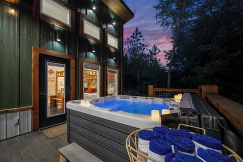Private deck hot tub with candles and forest view at sunset