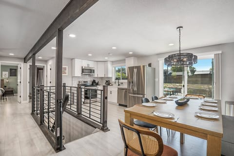 Bright and stylish open floor plan connecting the living room, dining area, and kitchen, with a chic staircase leading to the lower level.