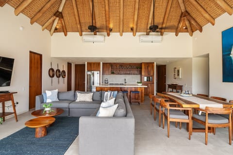 Inviting interiors blending modern design and natural textures, featuring a cozy sofa area and dining space under a palapa roof.