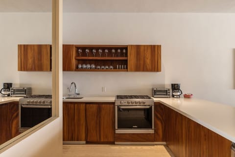 A fully equipped kitchen with rich wooden cabinetry, stainless steel appliances, and a sleek, minimalist design.