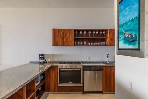 A fully equipped kitchen featuring rich wooden cabinetry, open shelving, and high-end appliances.