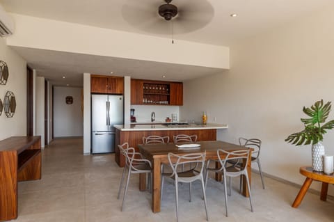 A stylish open-concept kitchen and dining area featuring wooden accents, bar seating, and top-of-the-line appliances.