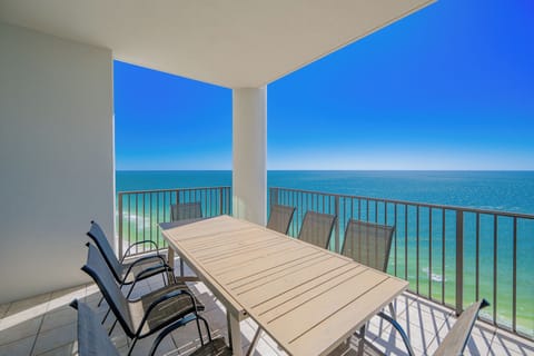 Enjoy meals with an impressive view from this spacious balcony featuring a large wooden dining table and comfortable chairs