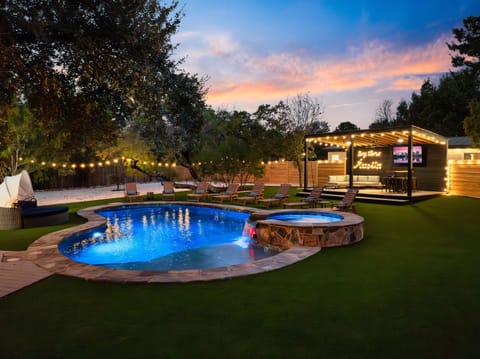 This backyard oasis with a glowing pool and hot tub is pure city magic at night.