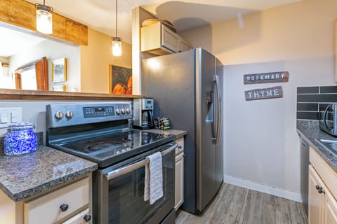A modern kitchen featuring stainless steel appliances, granite countertops, a backsplash, and decorative labels on the wall reading "Rosemary" and "Thyme.