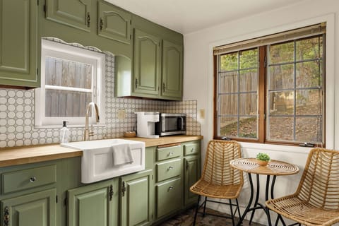 - Retro-inspired kitchen with green cabinets and farmhouse sink
- Sip coffee at a sunny bistro table with backyard views
- Fully equipped with essentials, microwave, and coffee maker