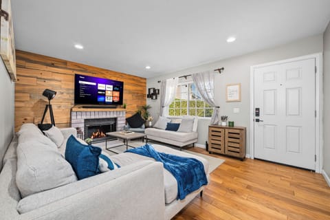 Modern living room with brick fireplace, wood accents, neutralsofas and greenery