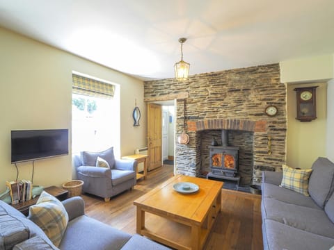 Living area, 2 sofas, armchair, coffee table, logburning stove, TV, wall clock and window