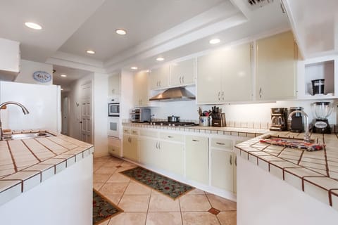 Retro-inspired design with tiled countertops, ample cabinetry, and modern stainless steel appliances