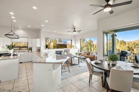 Living room with leather sofa, two chairs, open to kitchen and breakfast nook. Reflective 360 red rock view