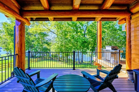 Relax on this charming covered deck featuring Adirondack chairs, a serene view of the lush greenery, and a cozy ambiance perfect for outdoor enjoyment.
