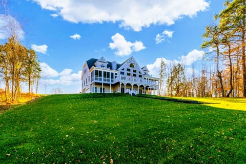 Grand lakeside home perched atop a lush green hill, offering breathtaking panoramic views