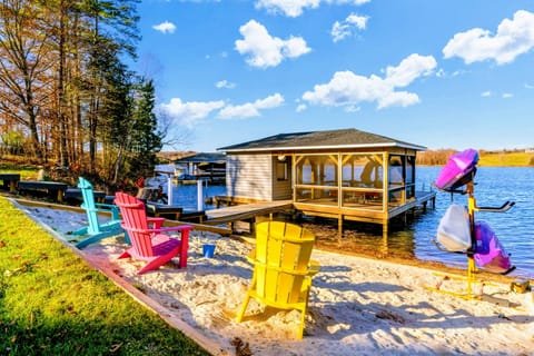 Charming lakeside beach with colorful Adirondack chairs, kayaks, and a covered dock for the perfect waterfront experience