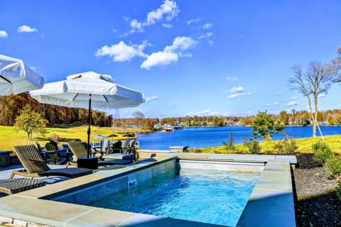 Relax in the luxurious hot tub with stunning lake views and comfortable outdoor seating under shaded umbrellas.
