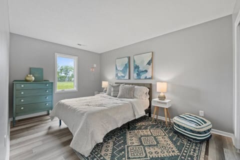 Elegant queen-sized bedroom with a spacious layout and large window, allowing natural light to create a bright and airy atmosphere.