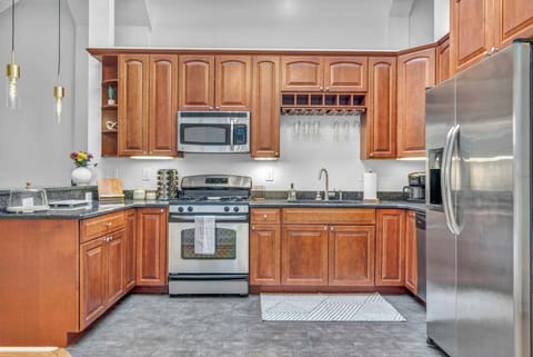 Illuminating the modern-meets-country ambiance. Natural wood cabinets exude warmth, their grain adding texture to the room's aesthetic. Against this backdrop, sleek granite countertops offer a contemporary touch, balancing the rustic charm.