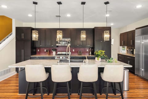 The modern kitchen features a sleek countertop with seating for four, offering a perfect space for casual meals or conversations. With high-end appliances and a functional layout, the kitchen combines style and practicality for a seamless cooking and
