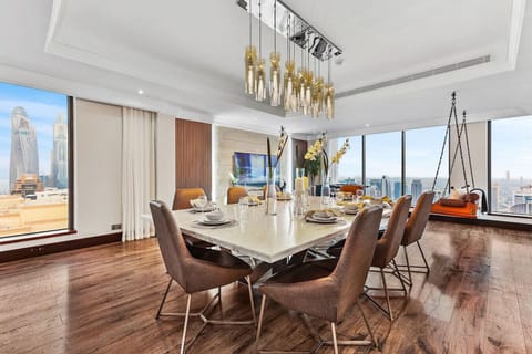 Luxurious dining area with modern furnishings, elegant lighting, and panoramic city views through large windows.