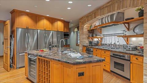 Spacious kitchen with triple fridges and large stone gas range