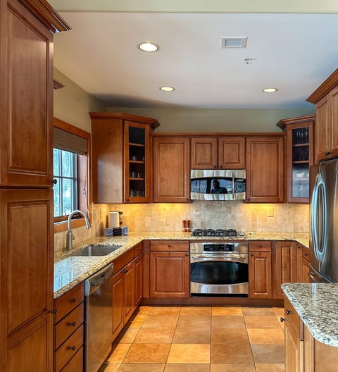 Fully-equipped kitchen with gas cooktop, oven, microwave, granite countertops, dishwasher, refrigerator, freezer, and more