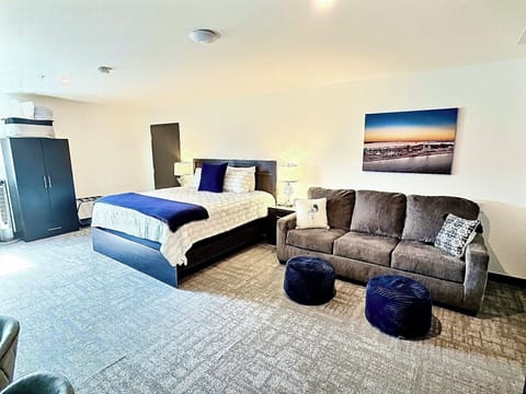 A bright, open room featuring a comfortable bed, work desk, ample storage, and a large TV, perfect for relaxing or working during your stay.