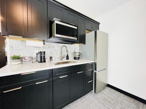 Stylish kitchen with dark cabinetry, stainless steel appliances, and a well-appointed coffee station for your morning needs.