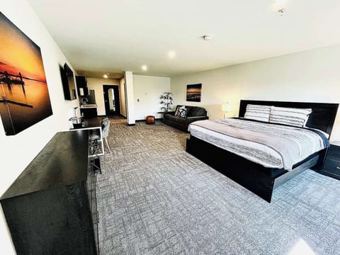 A bright, open room featuring a comfortable bed, work desk, ample storage, and a large TV, perfect for relaxing or working during your stay.