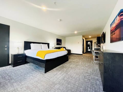 A bright, open room featuring a comfortable bed, work desk, ample storage, and a large TV, perfect for relaxing or working during your stay.