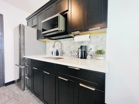 Stylish kitchen with dark cabinetry, stainless steel appliances, and a well-appointed coffee station for your morning needs.