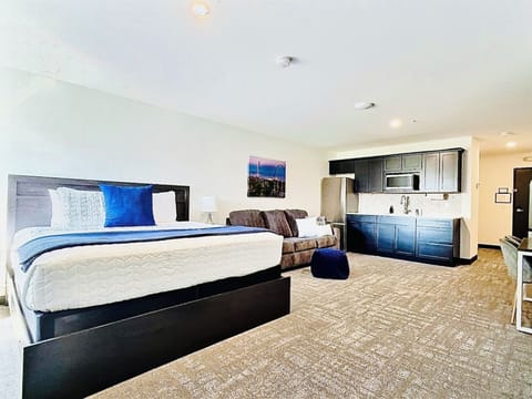 A bright, open room featuring a comfortable bed, work desk, ample storage, and a large TV, perfect for relaxing or working during your stay.