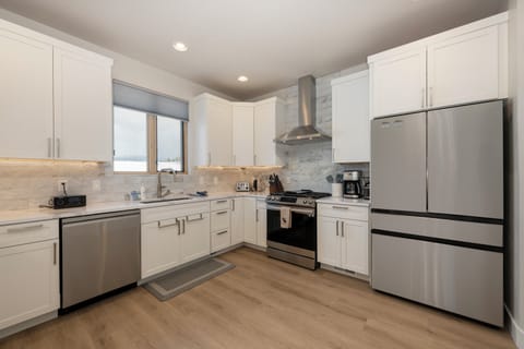 - Pristine kitchen boasts modern white cabinetry, marble backsplash, and essential appliances - Extra counter space and natural light from the window make cooking a delight - Perfectly designed for those who enjoy both functionality and style
