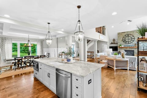 A spacious and modern kitchen with a large marble island, high-end appliances, elegant pendant lighting, and open access to the dining and living areas with views of the backyard.