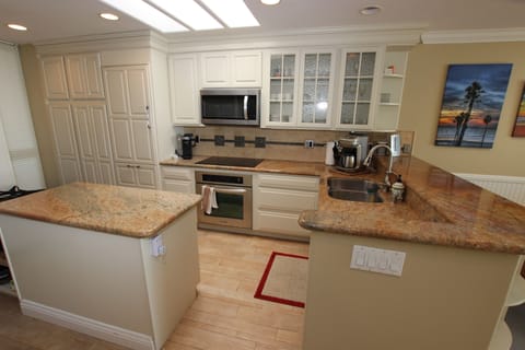 Kitchen with induction stove, oven, microwave and dishwasher. Tile floors.