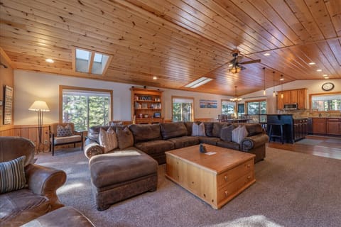 Large open great room (living room, dining area, kitchen) with river rock fireplace, beautiful furnishings, and 60 inch SmartTV.