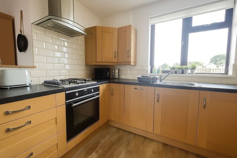 Kitchen with electric oven and hob, dishwasher, microwave, fridge/freezer, kettle, toaster and a range of pans and utensils.