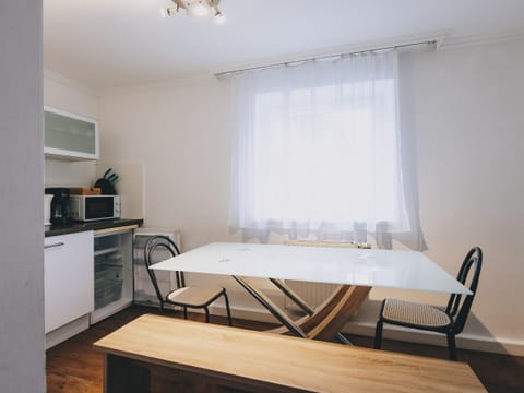 Dining area in the holiday apartment Areit Apartments by We Rent. Table with chairs and kitchen with microwave and stovetop.