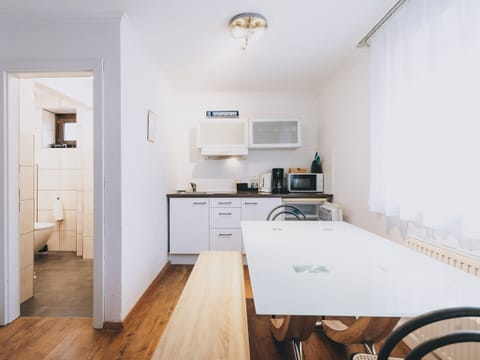 Dining area in the holiday apartment Areit Apartments by We Rent. Table with chairs and kitchen with microwave and stovetop.