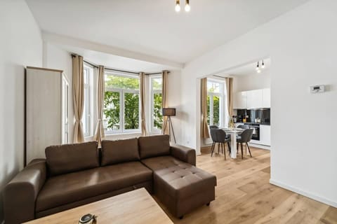 Offener Wohn- und Essbereich mit gemütlichem Sofa, viel Tageslicht und direkter Anbindung an die moderne Küche.