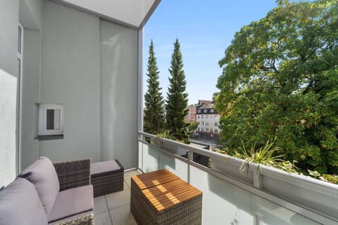 Der sonnige Balkon in Wilhelmshaven ist mit gemütlichen Sitzmöbeln ausgestattet und bietet einen schönen Ausblick auf Bäume und die Nachbarschaft.