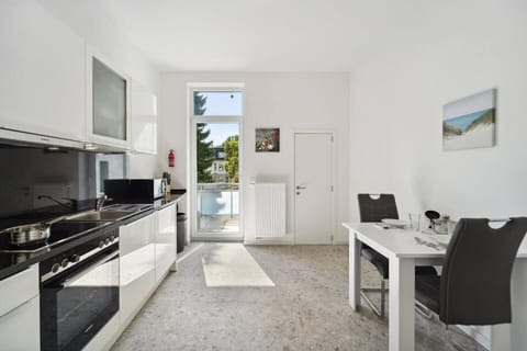 Die helle Küche ist mit modernen Geräten ausgestattet, bietet direkten Zugang zum Balkon und verfügt über einen kleinen Esstisch für gemeinsame Mahlzeiten.