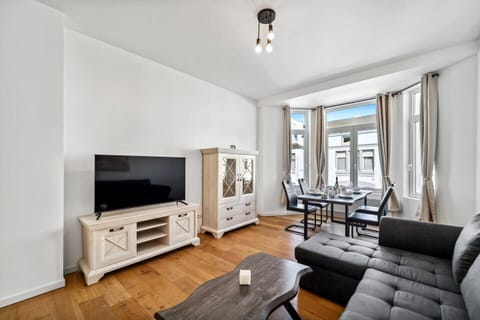 Das moderne Wohnzimmer überzeugt mit einem großen Ecksofa, einem Esstisch in der hellen Fensterfront, einem großen TV sowie stilvollen Holzmöbeln in freundlicher Atmosphäre.